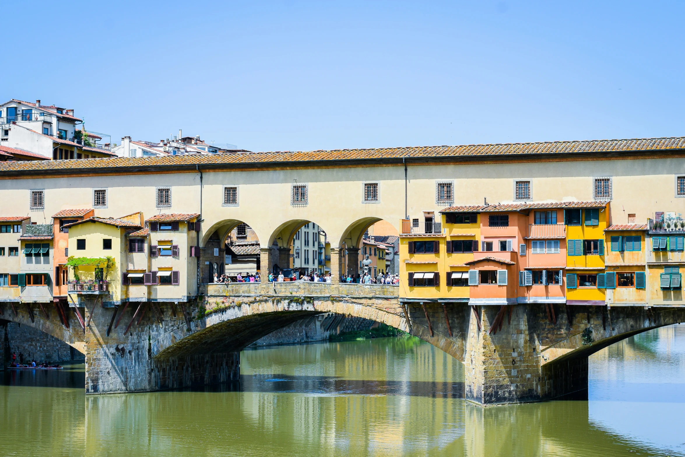 old brick bridge spanning the width of a river with buildings on it