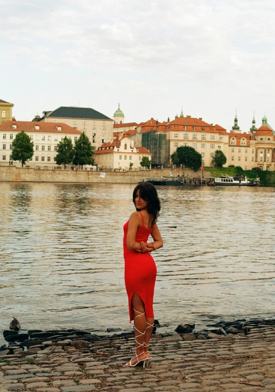 a woman in a red dress is standing on a shore