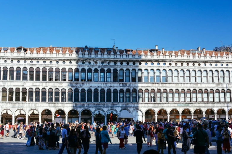 people standing outside of a large white building with arched windows