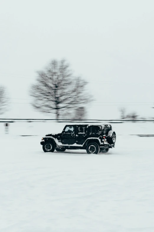 a black jeep driving down a snow covered road