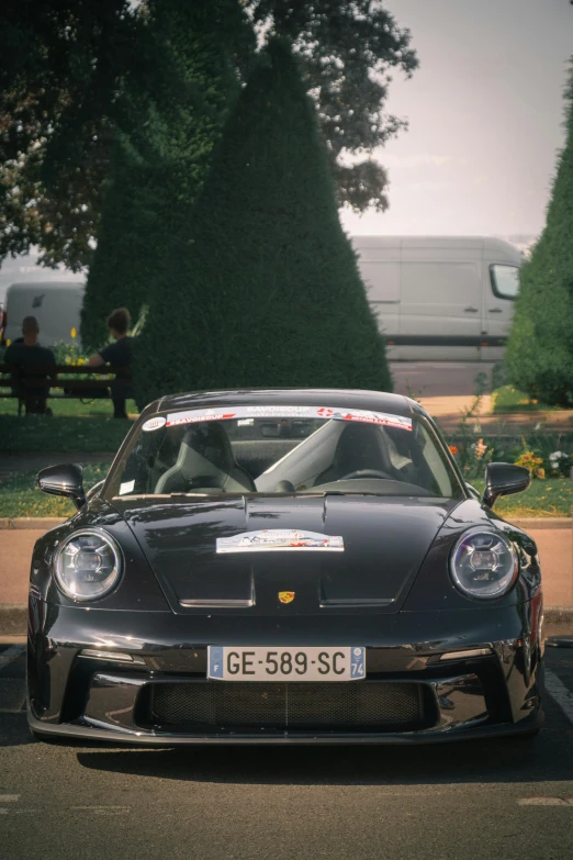 a grey sports car parked in front of a park bench