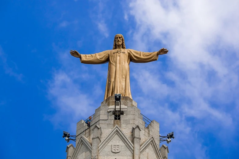a tall statue stands under a blue cloudy sky