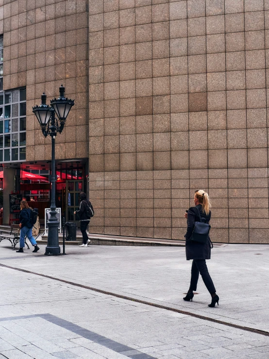 two people walk on the sidewalk near a building