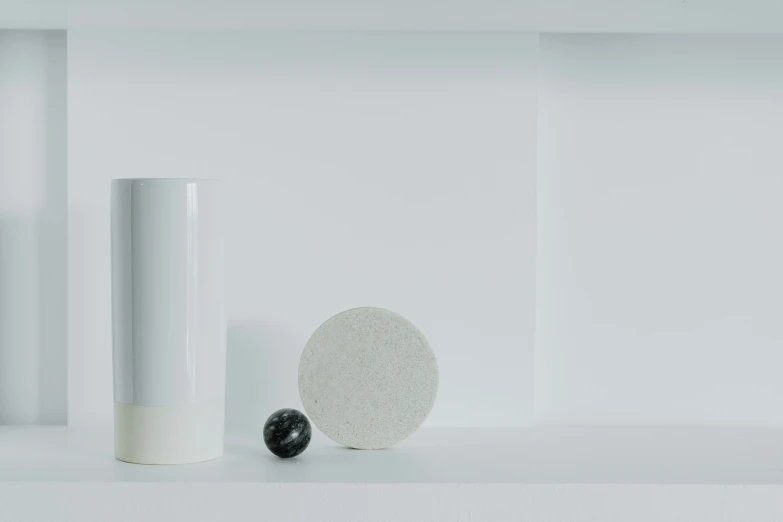 a vase, two balls and another large object are on the shelf