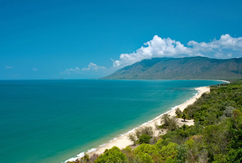 the view of the beach and water near a hill