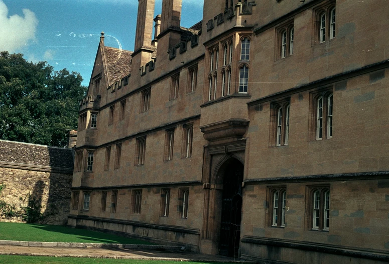 a large stone building with multiple windows near grass