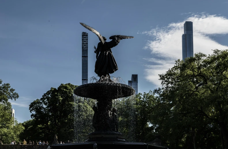 an eagle statue atop a fountain with some tall buildings behind it