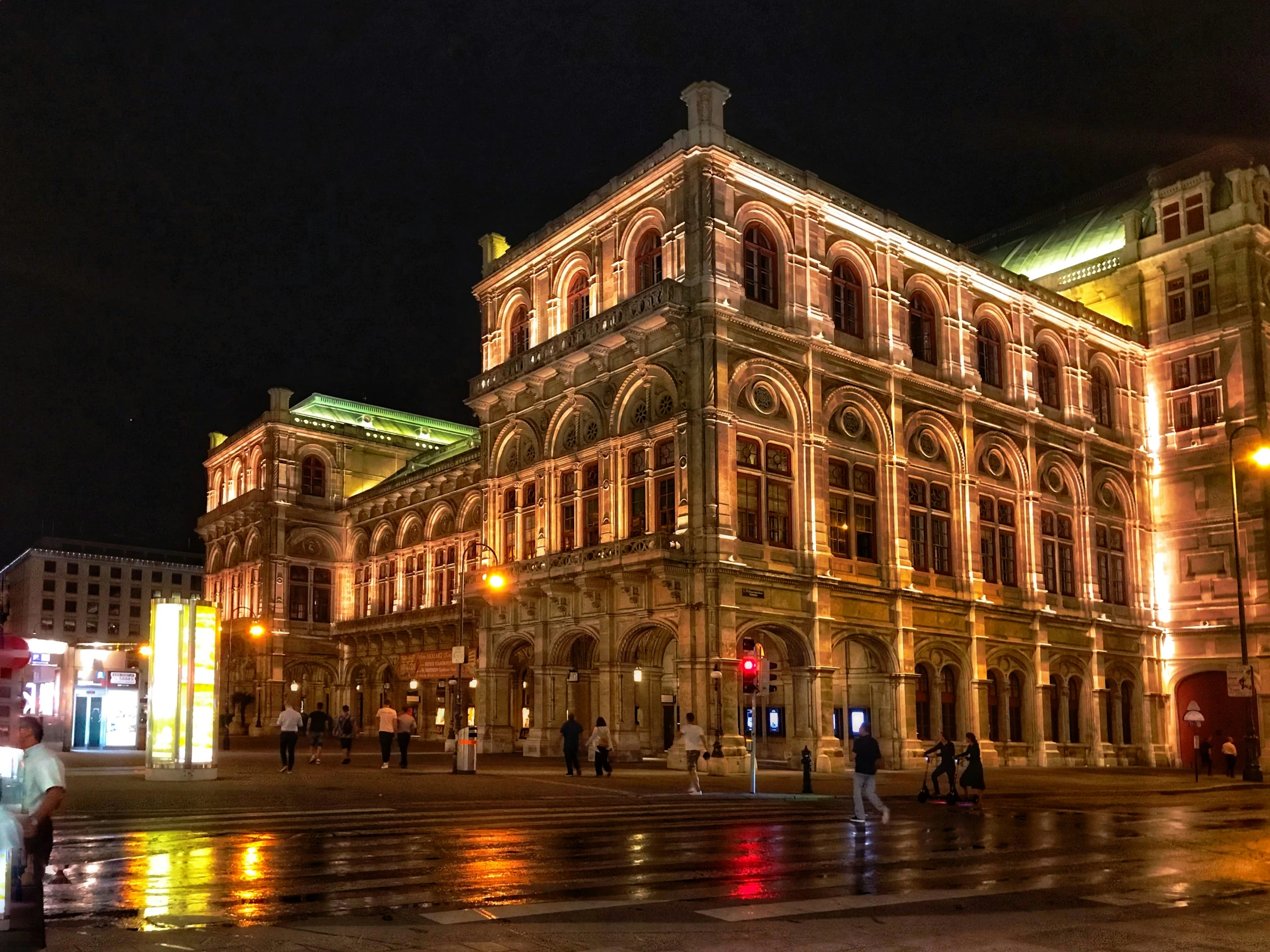 two people walking on a rainy street in front of an ornate building