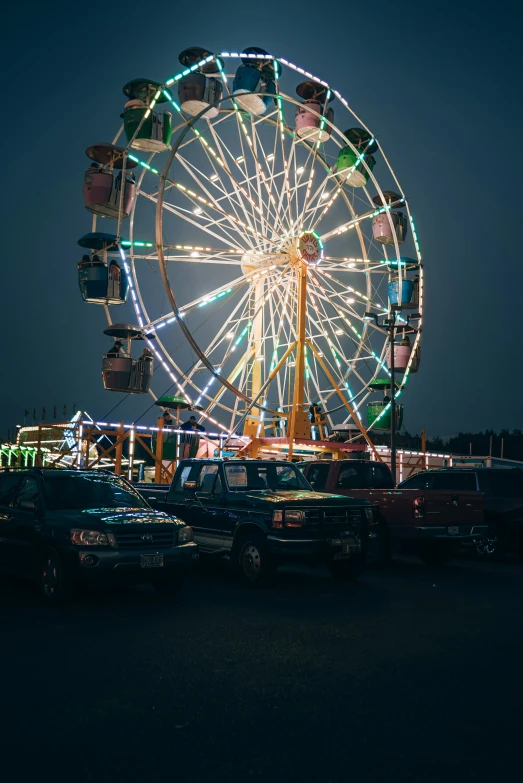 several cars parked near a ferris wheel and a park