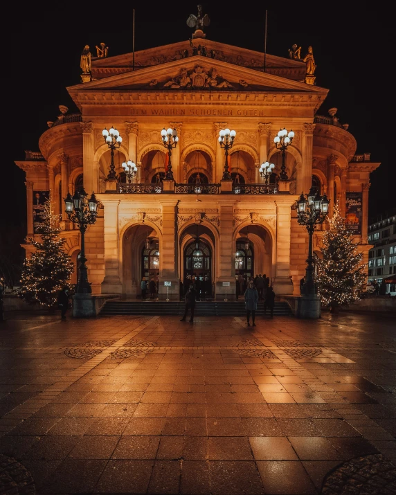 an old building lit up at night with christmas trees