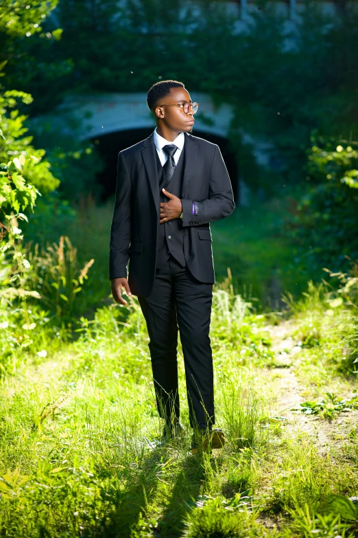 the man wearing the suit stands in front of the tree