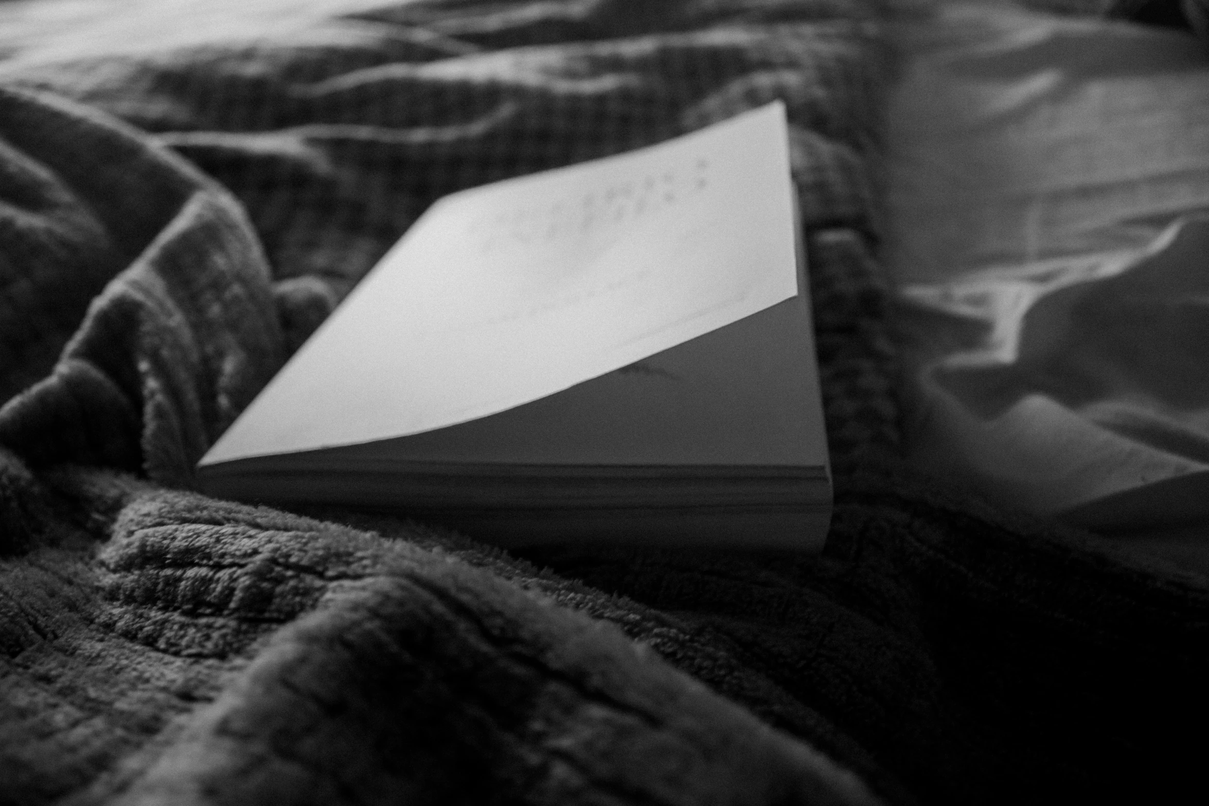 a book with a bookmark sits on a bed