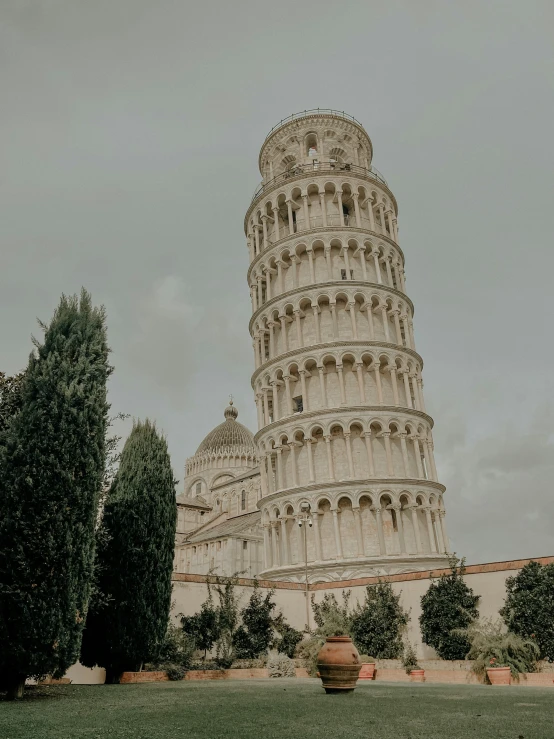 the leaning tower stands tall and has a big flower pot next to it