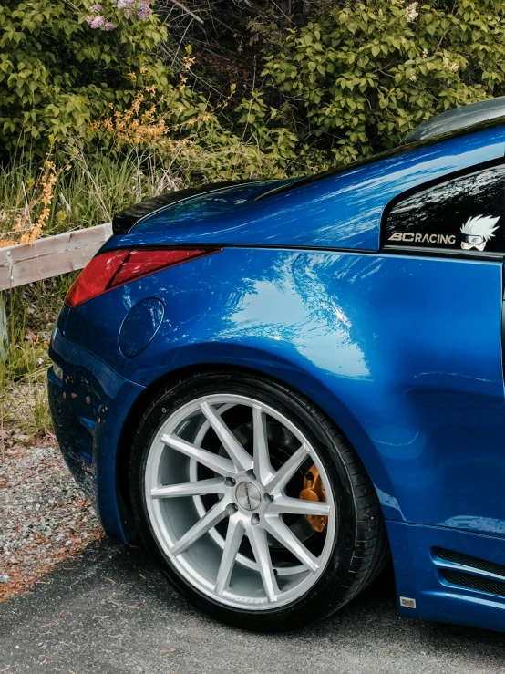 a blue car sitting in front of a bush