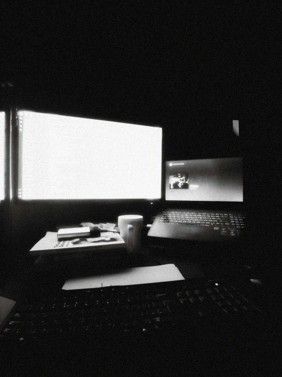 two monitors with laptops and papers on a table