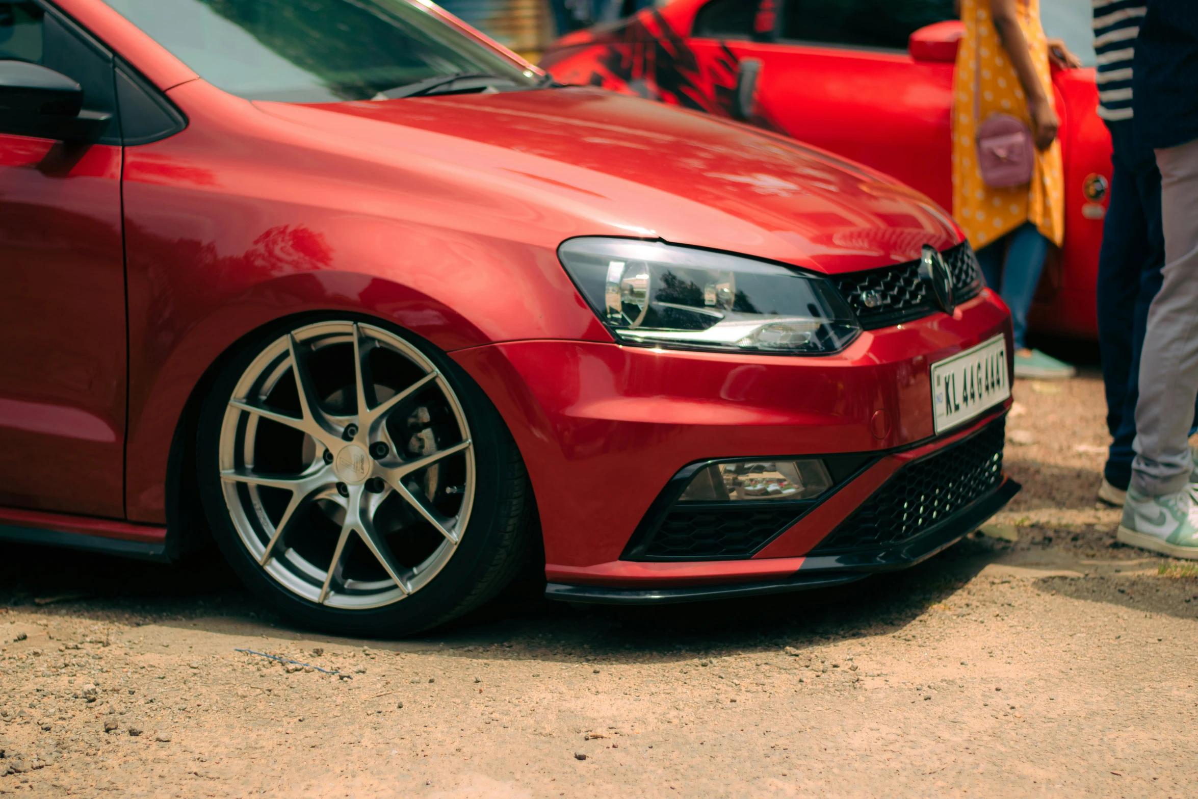 a car parked by some people with their wheels and bumpers