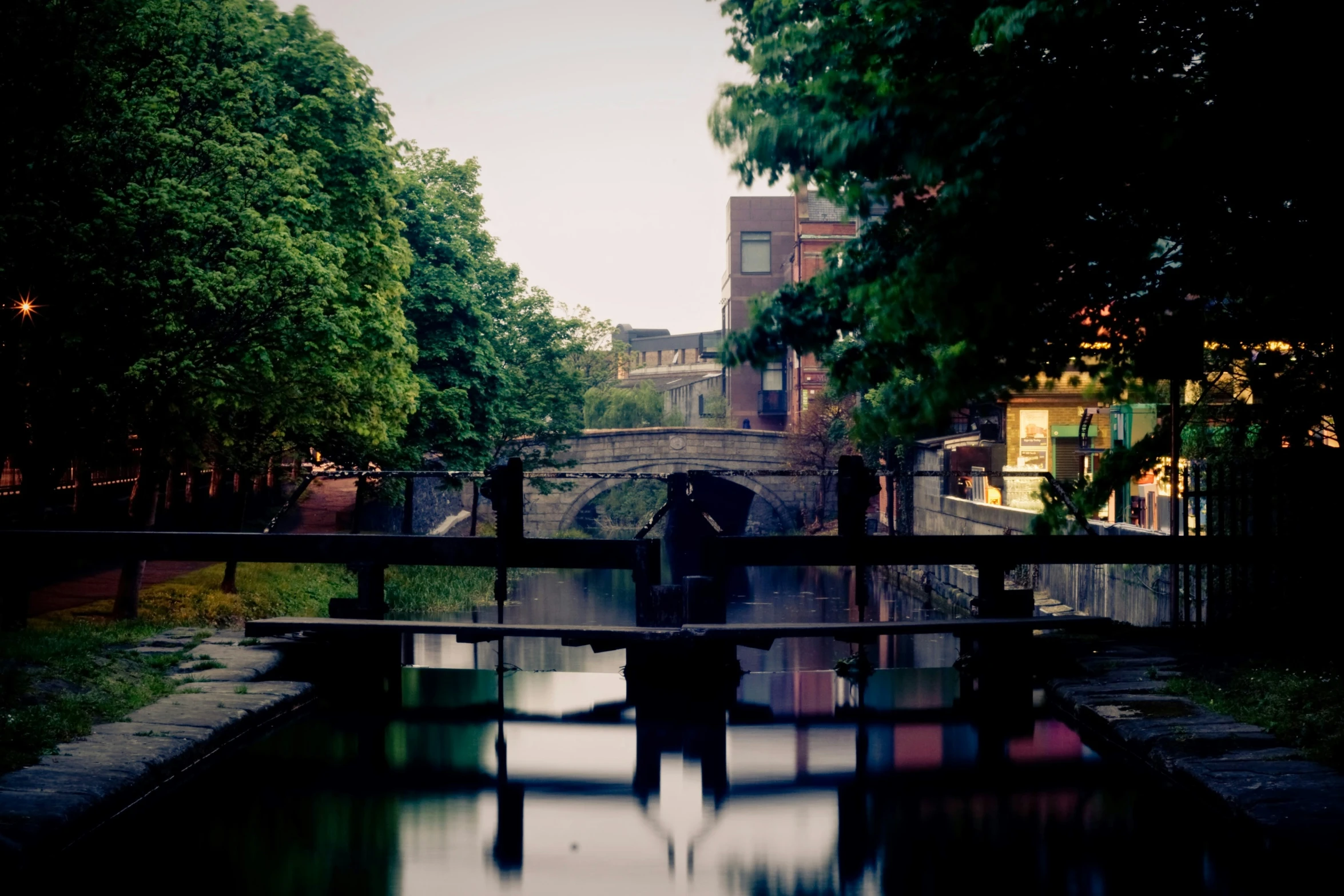 two people standing on a bridge that has water under it