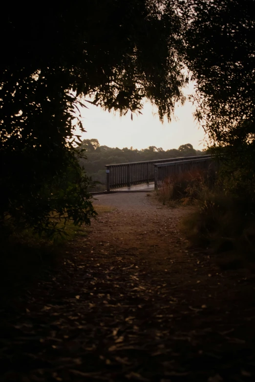 an empty dirt path with a fence at the end