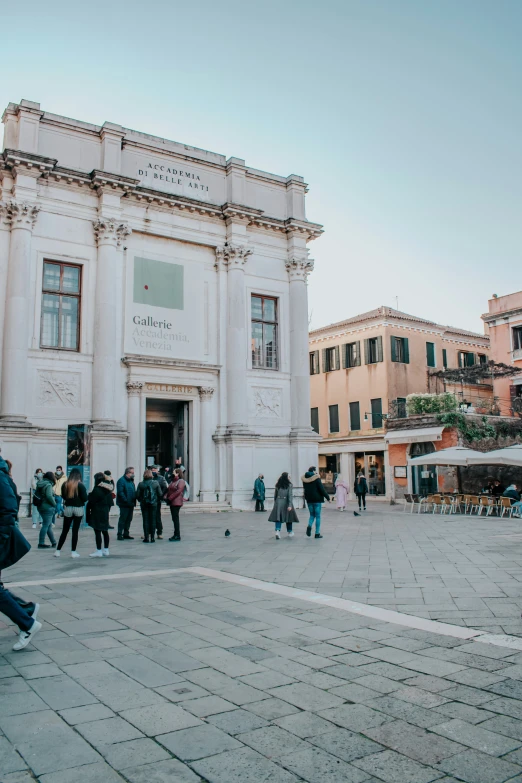 pedestrians walking in front of a large white building