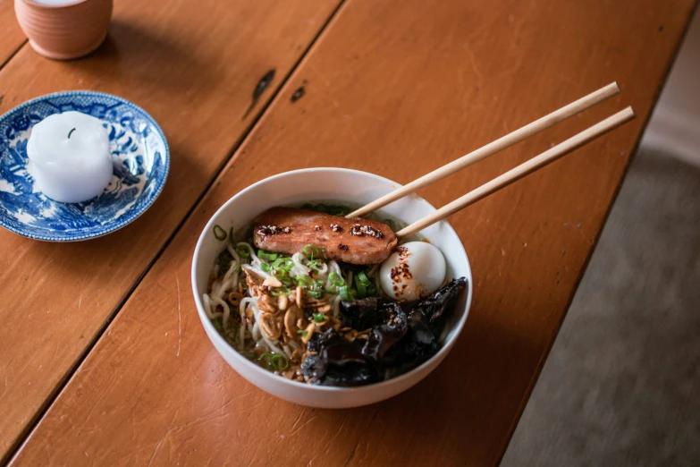 a bowl filled with soup and chopsticks next to two white dishes