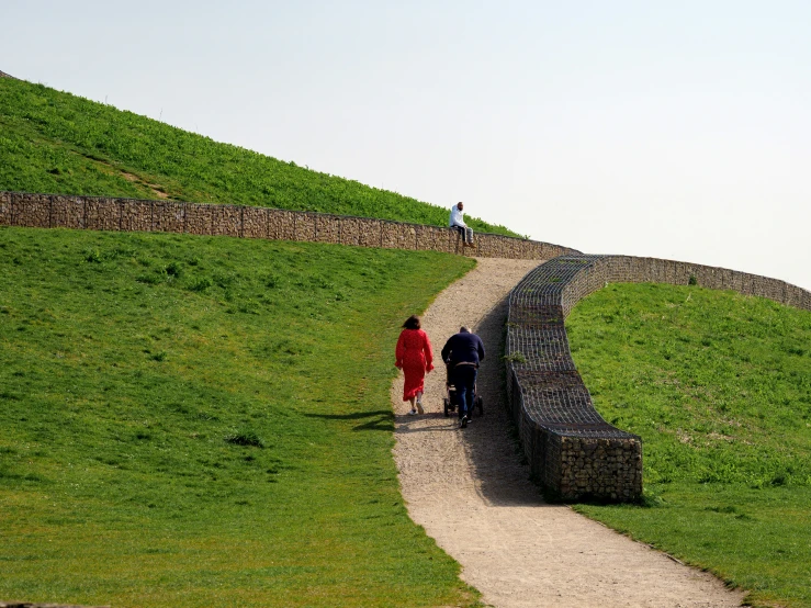 two people walking up a path near a small wall