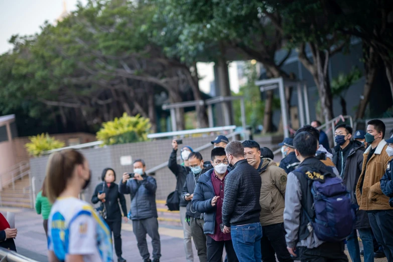 people are standing on the curb with masks covering their faces