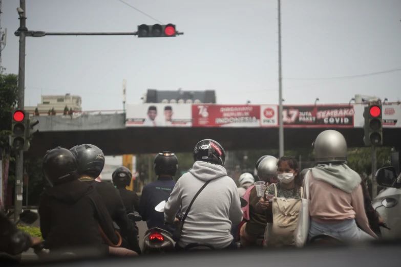 some people wearing helmets in the street while one is on a motorcycle