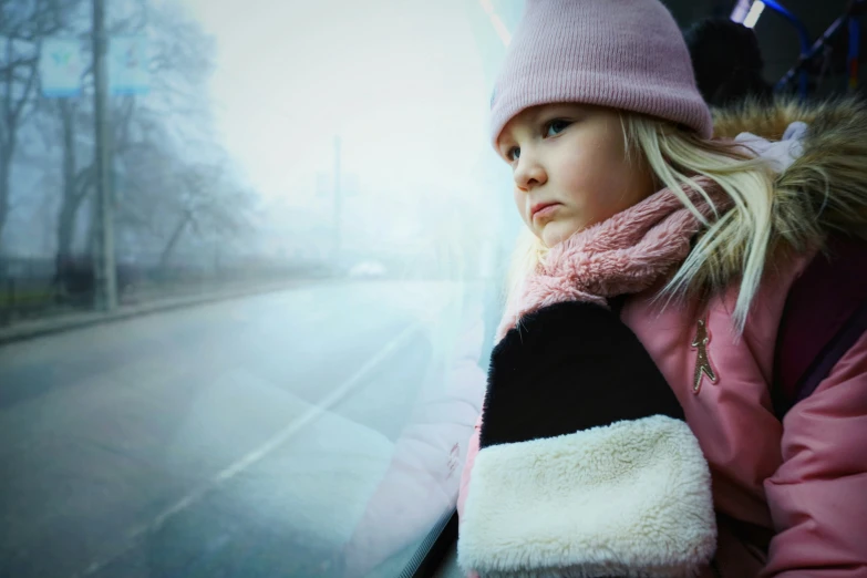 a little girl with a pink hat on a bus