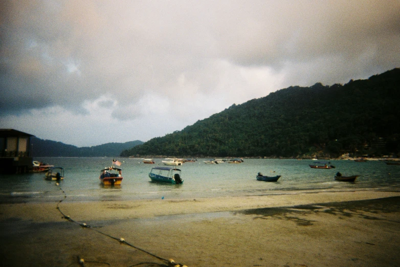 a cloudy and overcast sky is seen as several small boats float in a body of water