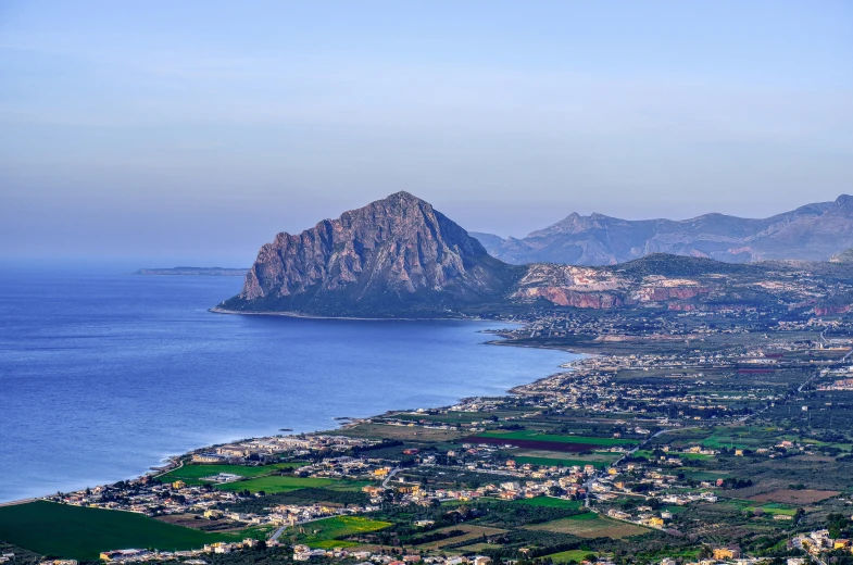 a view of a beach, water and mountains from high up in the sky