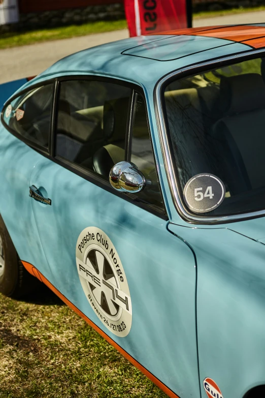 blue car parked on grass and with an orange line painted on the front