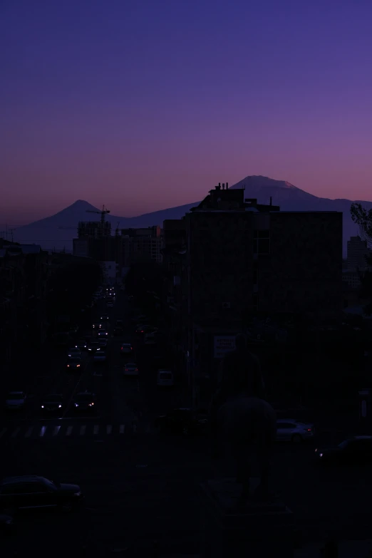 the sky is dark but a city street has cars