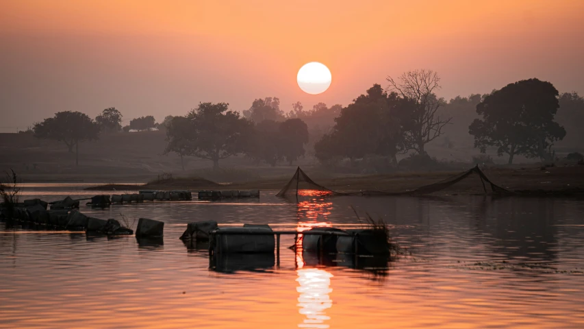 the sun is setting in a small lake