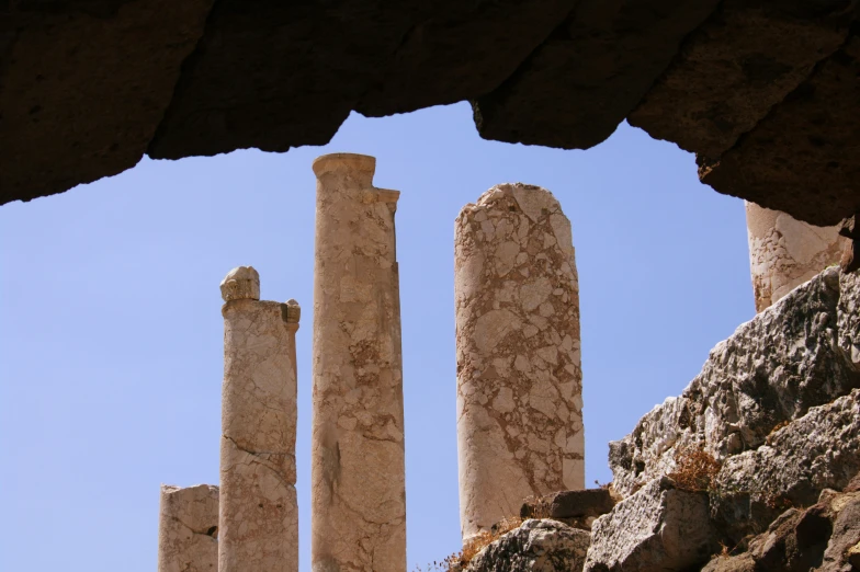 a few columns sitting in the background under a blue sky