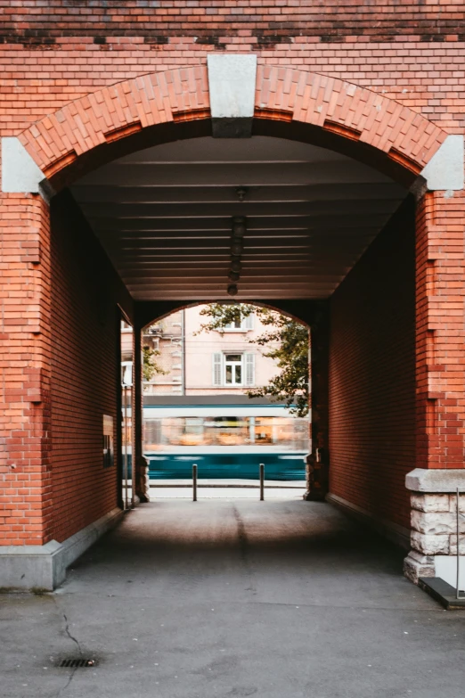 there is a train coming out from underneath a red brick structure