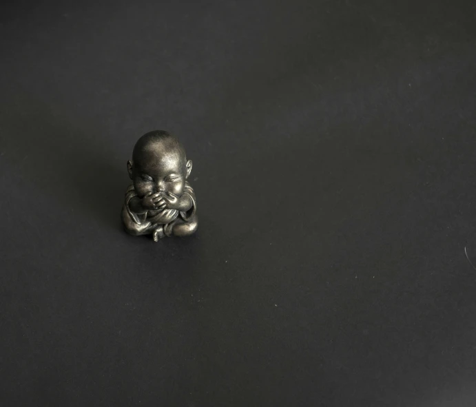 a small silver figurine is sitting next to a tiny figurine