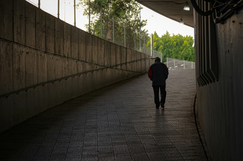 a woman walking down a brick sidewalk under a roof