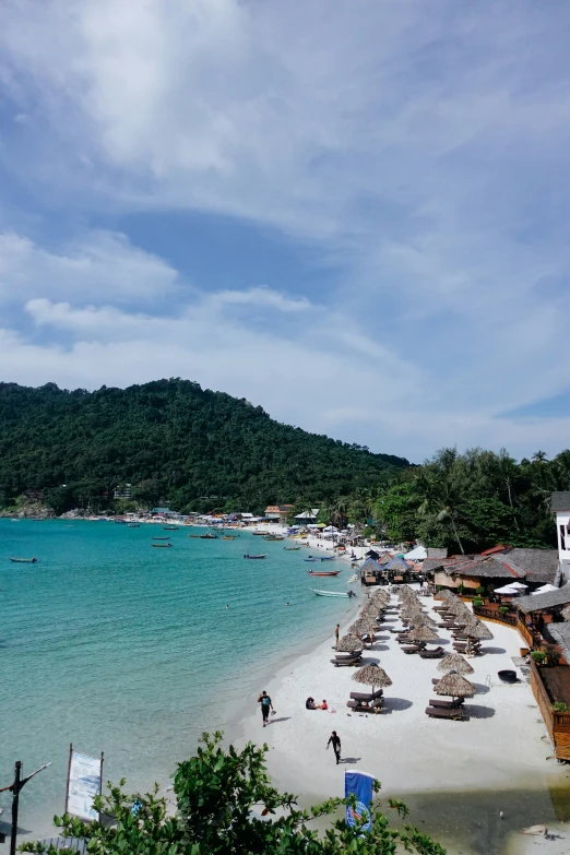 an idyllic, sandy beach with umbrellas and people