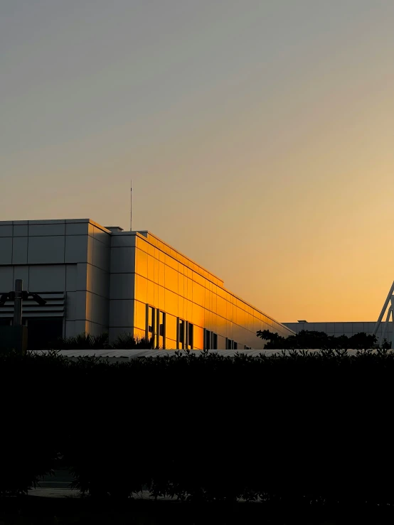 a building lit up at the top with the sun setting in the background