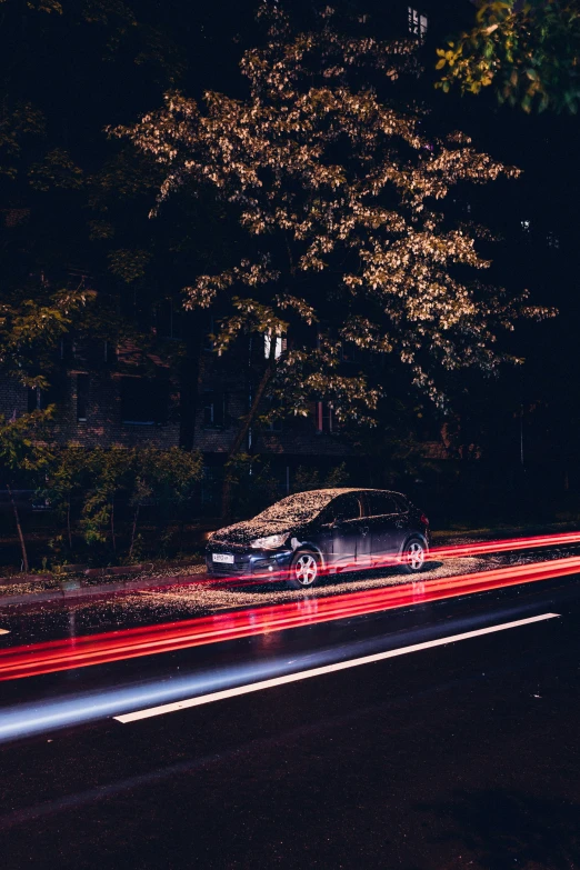 a car driving at night on a street with trees