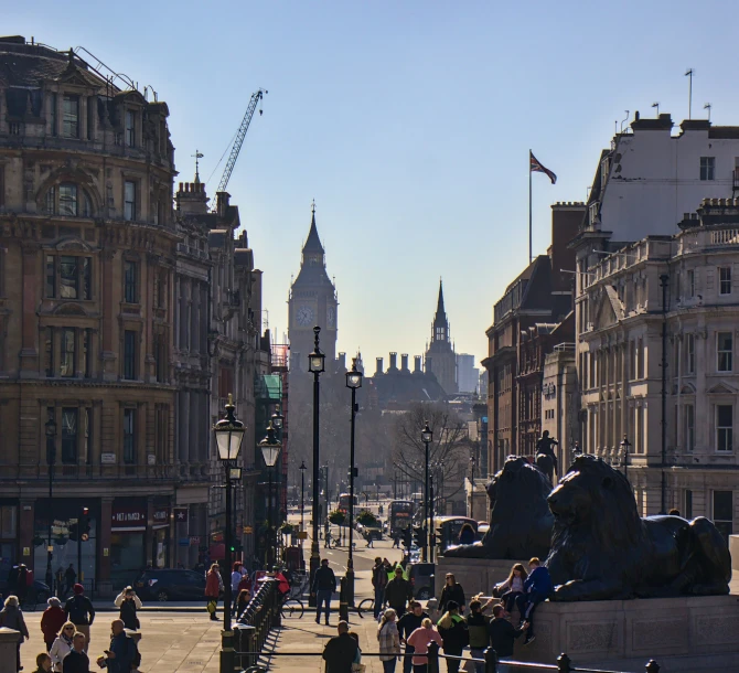 the city is busy with pedestrians and a clock tower in the background