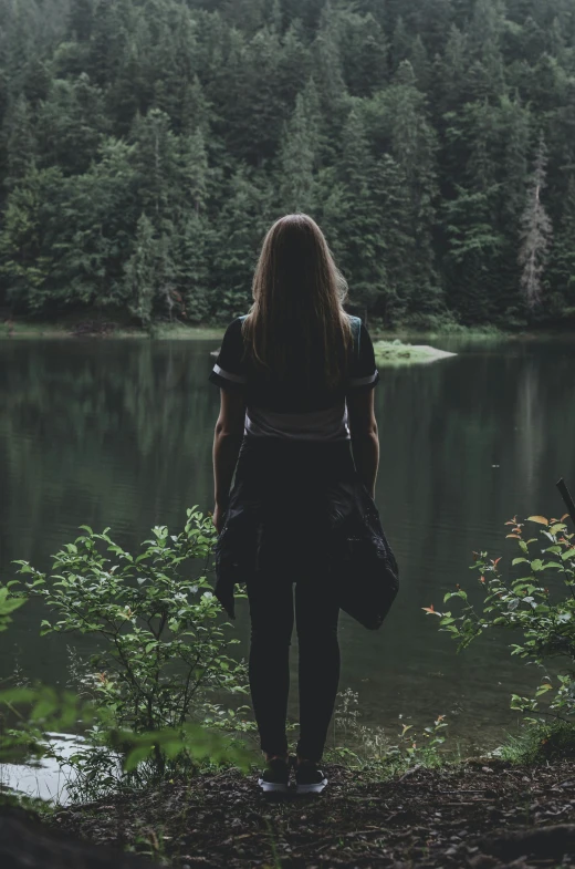 a person standing by the water near some trees