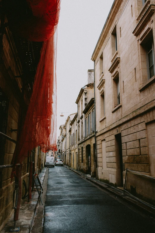 a narrow city street with old buildings and a red veil on the street