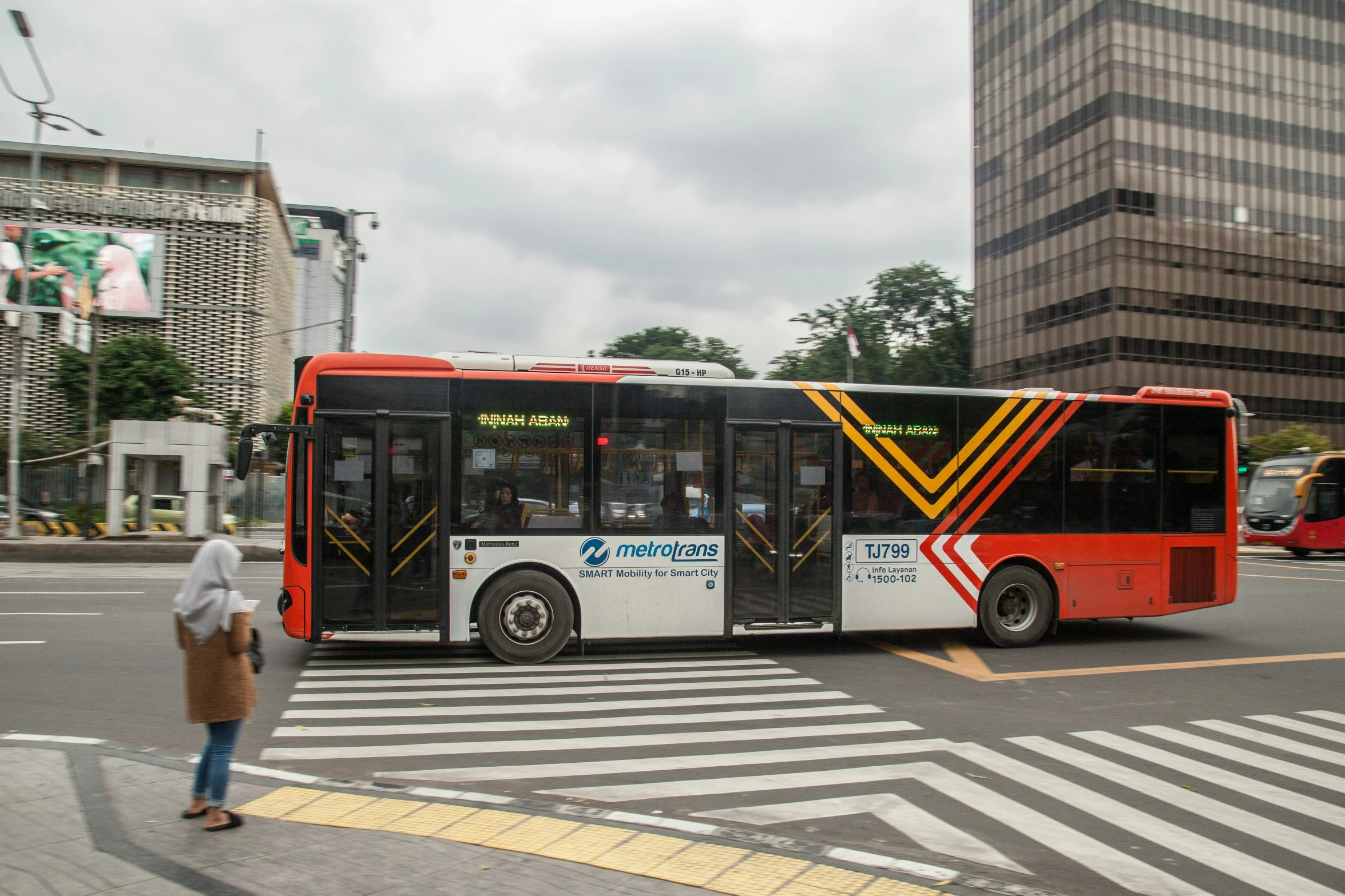 there is a man walking next to a red and white bus