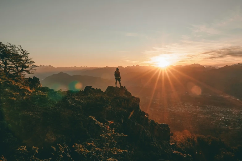 silhouette of a person standing on a mountain at sunset