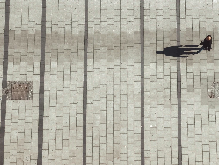 the shadow of a man sitting on a bench on a city street