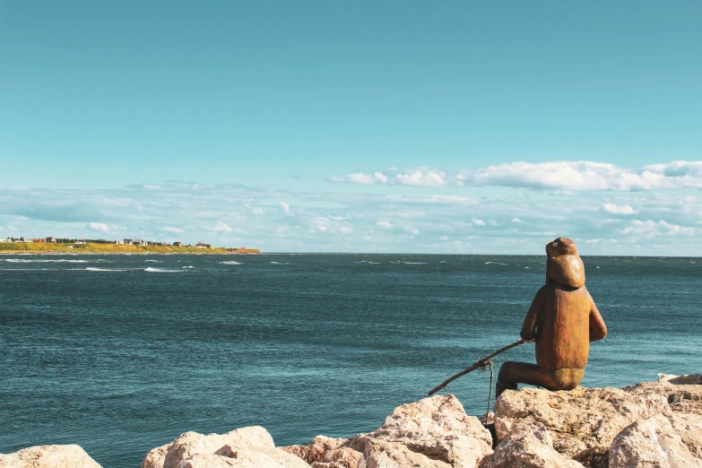 the figure is looking out over the water from a rocky cliff