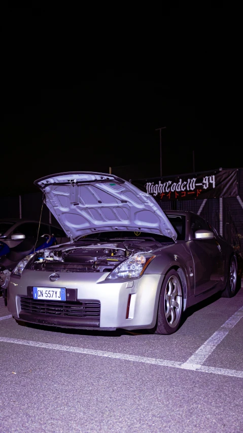 silver car with its hood open in the parking lot