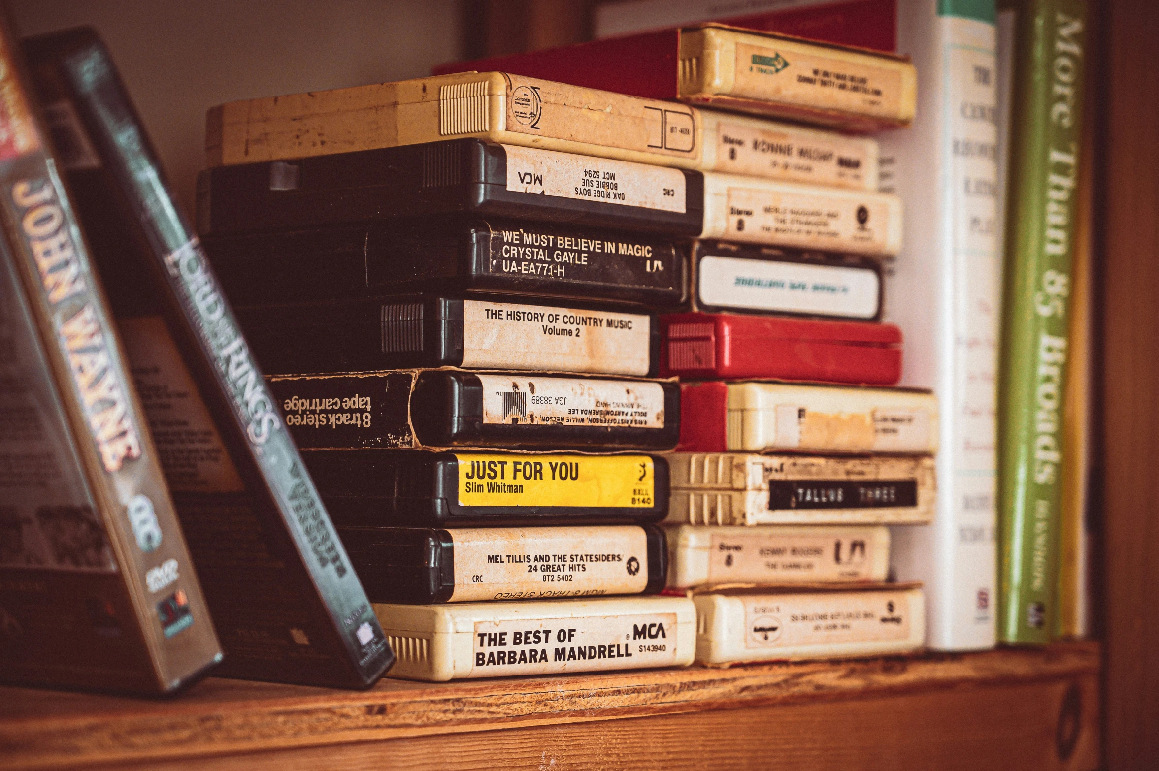 the stack of books in front of the bookshelf is stacked with several different types of hardback