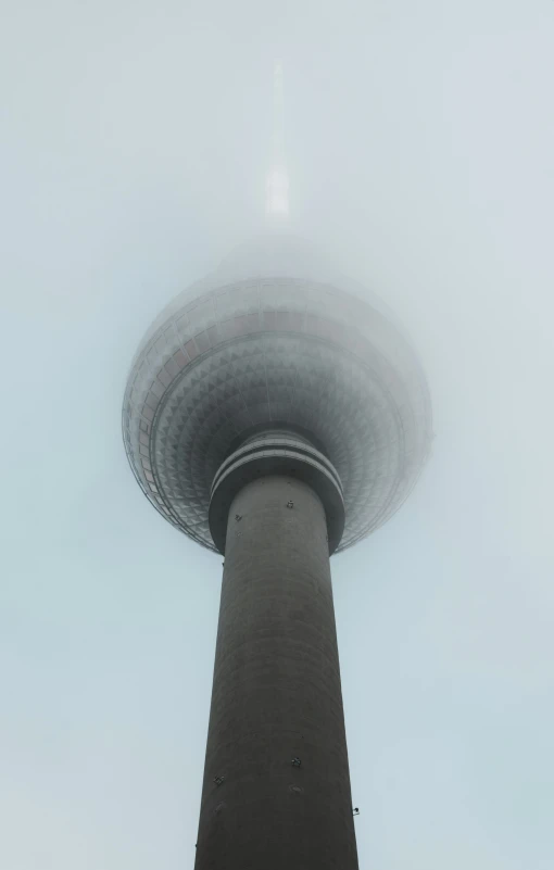 a tower on a foggy day with a plane flying overhead